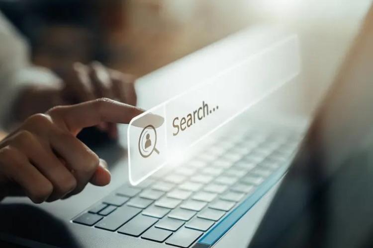 A finger tapping a glowing search bar with a person icon floating above a laptop keyboard, illustrating search engine marketing