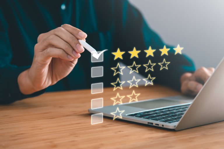 A hand ticking the top checkbox beside a row of five gold rating stars at a laptop, illustrating a focus on quality